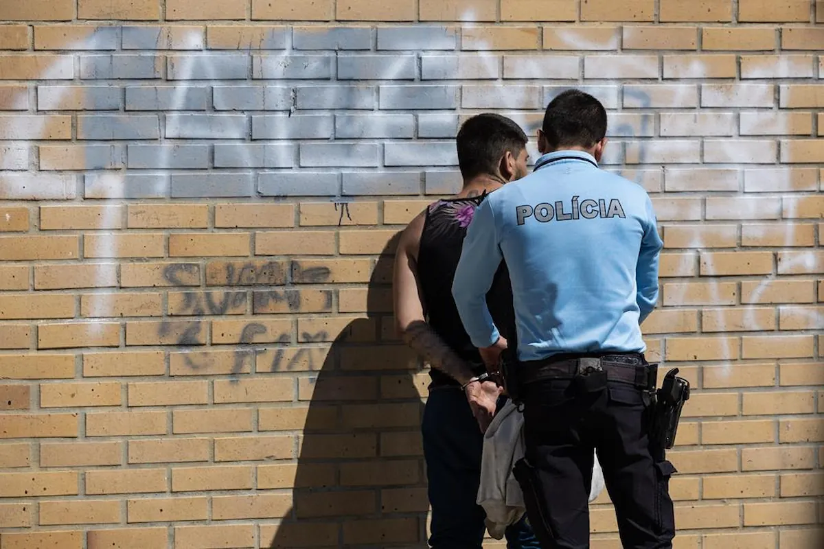 A propósito do tema "registo criminal condenação", vemos alguém encostado à parede enquanto é algemado.