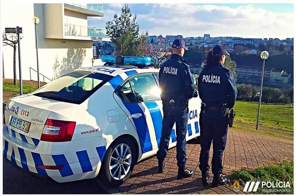 A propósito de processo crime e ofendido, vemos dois agentes da polícia de segurança pública a olhar para a paisagem e uma viatura sob o fundo.